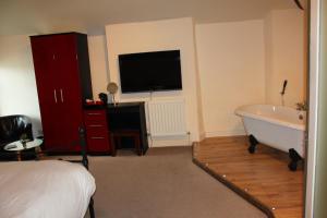 a bedroom with a bed and a tub and a television at The Olive Branch in Ilfracombe