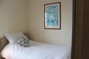 a bedroom with a white bed with a picture on the wall at The Olive Branch in Ilfracombe