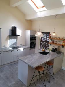a kitchen with white cabinets and a large island with bar stools at Three Peaks View Cottage BD23 4SP in Wigglesworth
