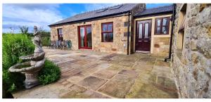 a stone house with a patio in front of it at Three Peaks View Cottage BD23 4SP in Wigglesworth