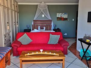 Una sala de estar con un sofá rojo y una cama. en Walkerbay Accommodation, en Gansbaai
