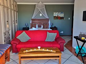 a living room with a red couch and a bed at Walkerbay Accommodation in Gansbaai
