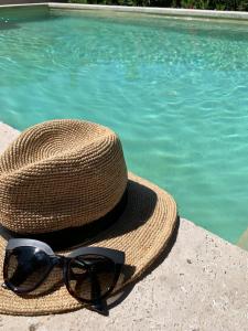 un sombrero y gafas de sol sentados junto a una piscina en Le clos des oliviers, en Aubignan