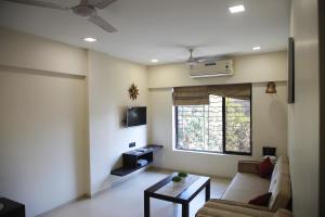 a living room with a couch and a table and a window at Lite Stays - Vile Parle East in Mumbai