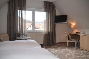 a hotel room with a bed and a desk and a window at Castell Hotel & Restaurant in Leinsweiler