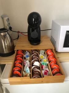 a wooden tray of chocolate covered donuts next to a coffee maker at Le printemps de mélusine in Niort