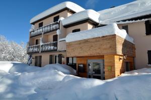 ein schneebedecktes Gebäude mit einem Stapel Schnee in der Unterkunft Logis Hôtel Le Griou in Saint-Jacques-des-Blats