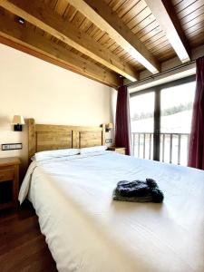 Un dormitorio con una gran cama blanca con una gran ventana. en Apartaments Gran Vall, en La Molina