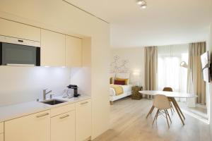 a white kitchen with a table and a bedroom at The Passage - Urban & Lifestyle Hotel in Basel