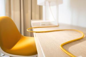 a yellow chair sitting next to a desk at The Passage - Urban & Lifestyle Hotel in Basel