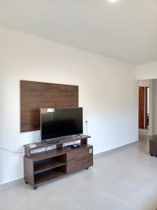 een woonkamer met een flatscreen-tv op een houten entertainmentcentrum bij Casa individual com piscina e area gurmet in Santa Cruz Cabrália