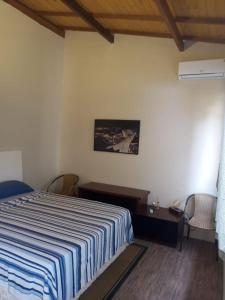 a bedroom with a bed with a blue and white striped blanket at casa spa in Rio das Ostras