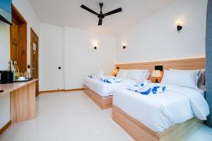 duas camas num quarto de hotel com paredes brancas em La Palma Villa em Ukulhas