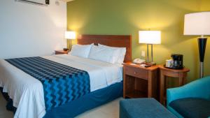Holiday Inn Express Cabo San Lucas, an IHG Hotel في كابو سان لوكاس: غرفة فندقية بسرير كبير وكرسي
