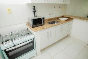 a kitchen with a microwave and a sink at Apartamento para família - Duplex Mont Moriá in Porto Seguro