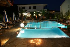 a swimming pool at night with chairs and umbrellas at Afroditi in Panormos Skopelos