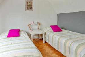 two beds in a room with pink pillows at Maison de 2 chambres a Guimaec a 500 m de la plage avec vue sur la mer jardin amenage et wifi in Guimaëc