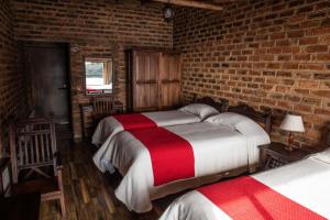 a bedroom with two beds and a brick wall at Hotel Refugio Pozo Azul in Aquitania