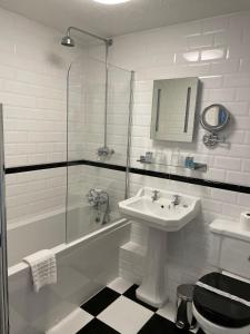 a white bathroom with a sink and a shower at Ebury Hotel Cottages and Apartment's in Canterbury