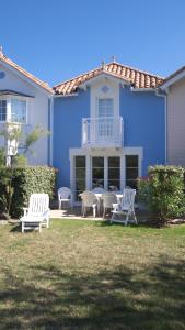 een blauw huis met twee witte stoelen en een tafel bij Maison Vendée 2ch piscine wifi in Talmont