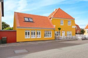 a yellow house with an orange roof on a street at 1 Skøn og lyst indrettet feriehus i Skagen in Skagen