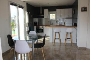 een keuken met een glazen tafel en witte stoelen bij Maison récente, deux chambres, à 10 minutes en voiture des plages in Moëlan-sur-Mer