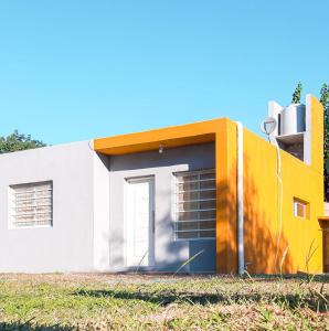 a house with a yellow and white facade at La Soñada - cabañas in Cruz del Eje