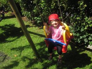 a little girl is sitting on a swing at Appartement Gästehaus Aloisia in Hippach