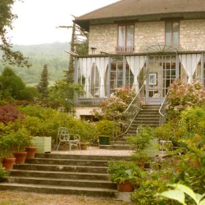 
a house with a balcony and a large window at La Pluie de Roses in Giverny
