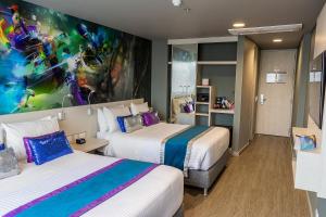 波哥大的住宿－布拉克濤爾尊貴酒店，酒店客房设有两张床,墙上挂有绘画作品