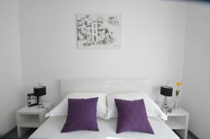 a bedroom with a white bed with purple pillows at Downtown Main Street Studio in Zadar