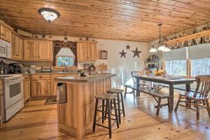 a kitchen with wooden cabinets and a table with bar stools at Outdoor Adventure - Charming Cabin with Hot Tub in Sautee Nacoochee