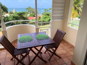 a table and chairs on a balcony with a view of the ocean at Studio Green Jungle in La Trinité