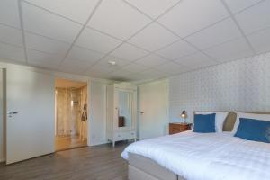 a bedroom with a large white bed with blue pillows at Herberg de Griffioen in Wolphaartsdijk
