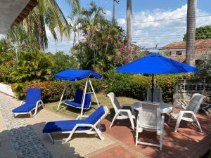 eine Terrasse mit blauen Sonnenschirmen und Stühlen sowie einem Tisch in der Unterkunft Casa El Peñon in Girardot