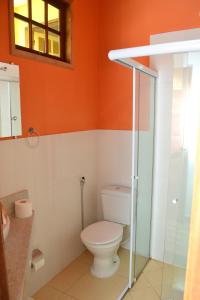 a bathroom with a toilet and an orange wall at Pouso Paratiense Jabaquara in Paraty
