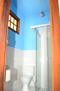 a bathroom with a toilet and a glass shower at Pouso Paratiense Jabaquara in Paraty
