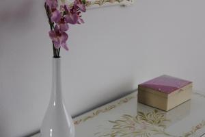 a white vase with flowers and a box on a table at Apartamento Neptuno in Benagil