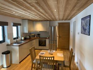 a kitchen with a wooden table with chairs and a dining room at Just Morzine - Apartment Luna in Morzine