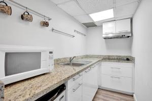 eine weiße Küche mit einer Spüle und einer Mikrowelle in der Unterkunft Luxe 2br1bath South beach 1 min walk from ocean in Miami Beach