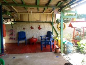 un porche cubierto con 2 sillas y pollos en la pared en Residência da Cláudia, en Fernando de Noronha