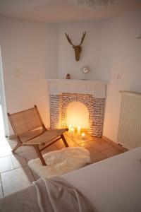 a living room with a fireplace and a chair and candles at Oboho - Le gîte bohème (Pieds dans l’eau - Lit King Size - Jardin) in Esneux