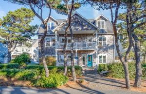 a large white house with a balcony and trees at Sunset 389 in Depoe Bay