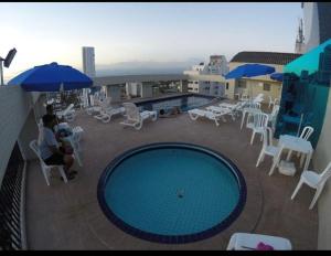 a balcony with a swimming pool and tables and chairs at Flat Sao Vicente in São Vicente
