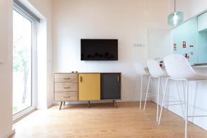 sala de estar con TV y taburetes blancos en Casa 53, en Aveiro