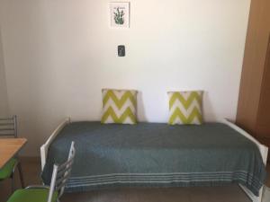 a bedroom with a bed with green and yellow pillows at Caleta del Sur in Las Grutas