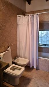 y baño con aseo y cortina de ducha. en Casa en las Sierras de Córdoba en Unquillo
