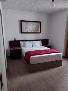 a bedroom with a large bed with a red blanket at Hotel Don Quijote Plaza - Guadalajara Centro Historico in Guadalajara