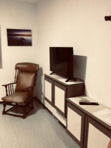 a living room with a chair and a television at Casa Mar Azul in Arinaga