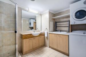 a bathroom with a sink and a washing machine at Rolling Surf Resort in Caloundra